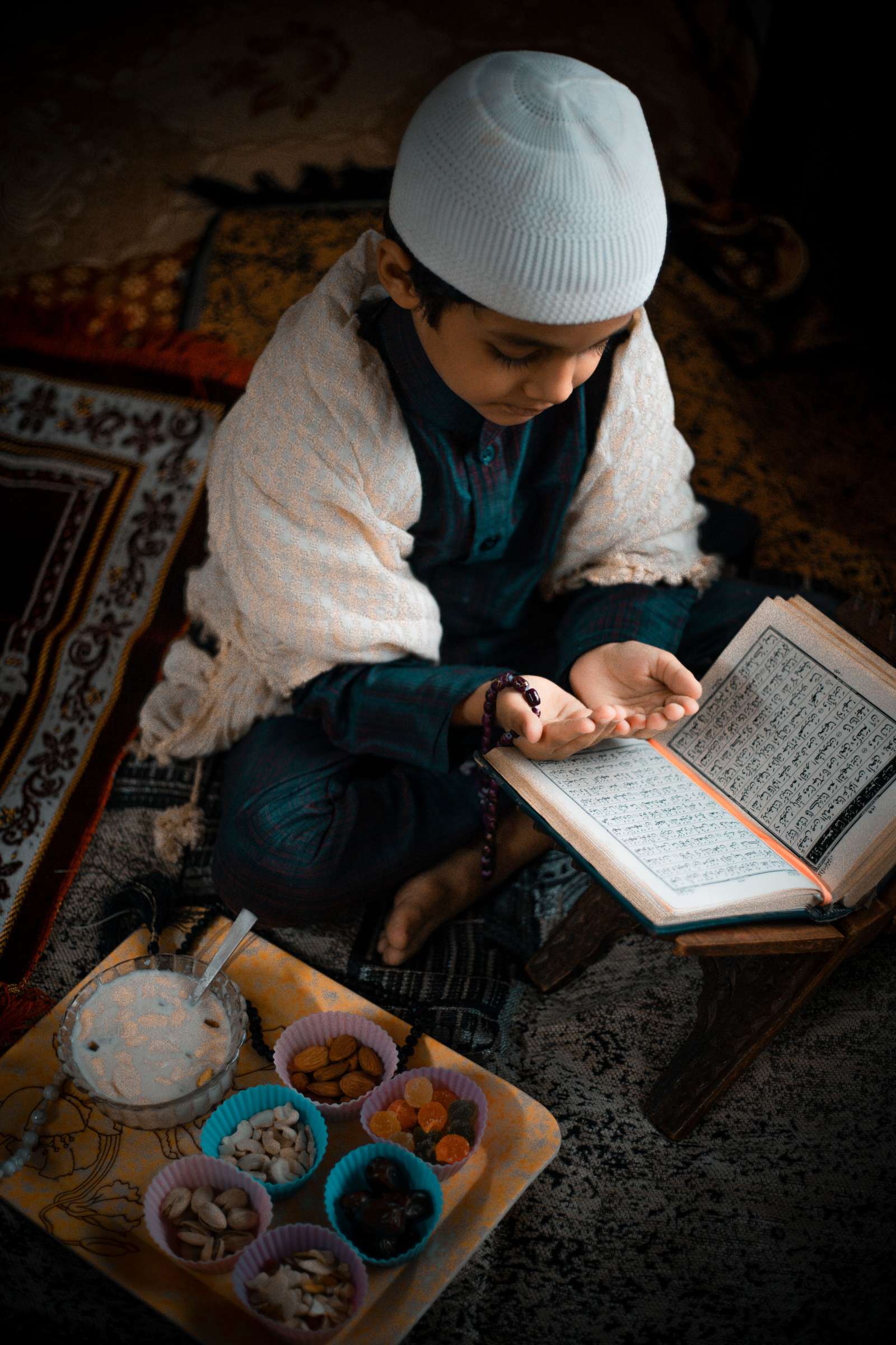 A child's hands resting on an open Quran